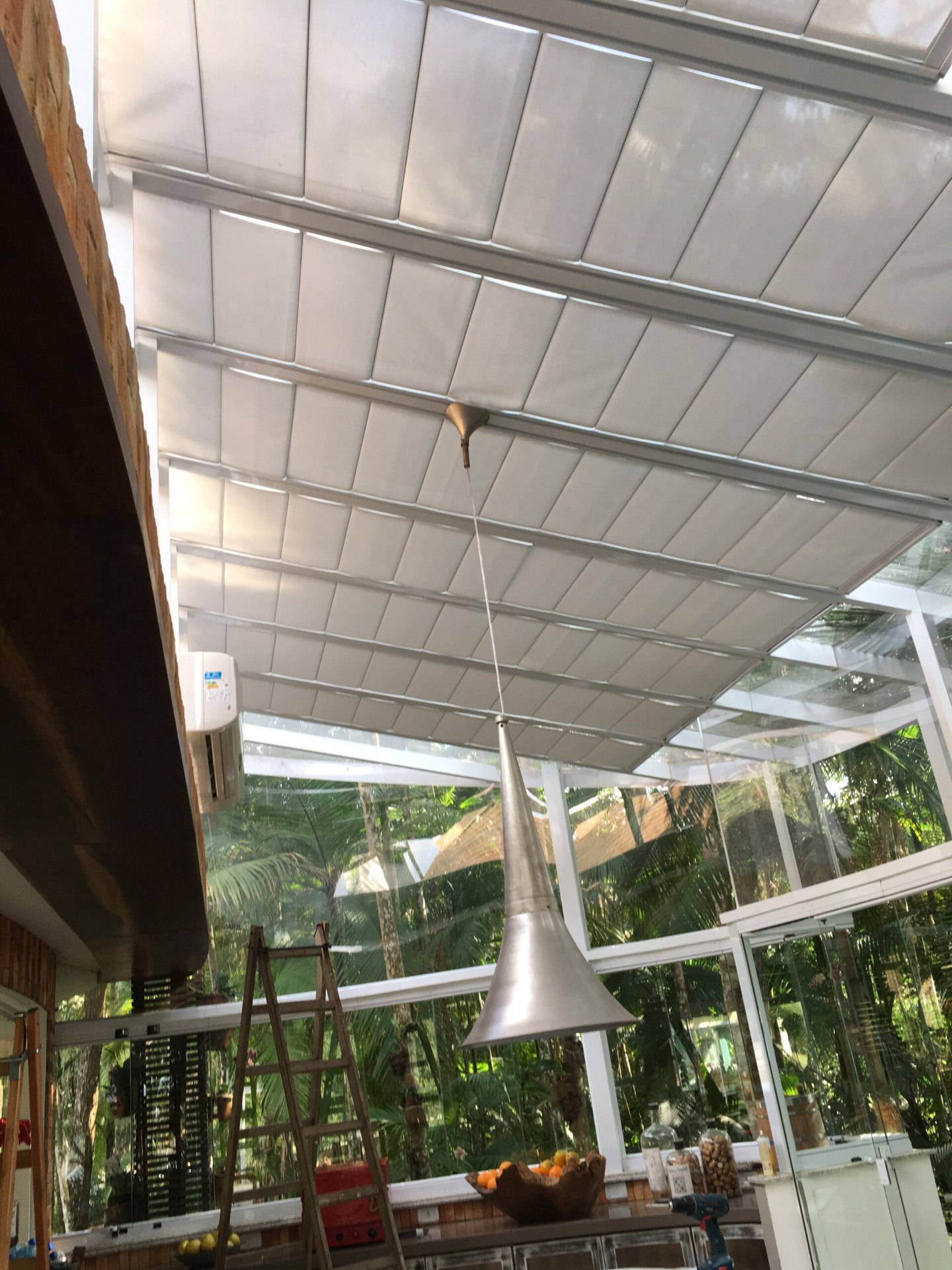 Cortinas claras sob cobertura envidraçada em área com mesa.